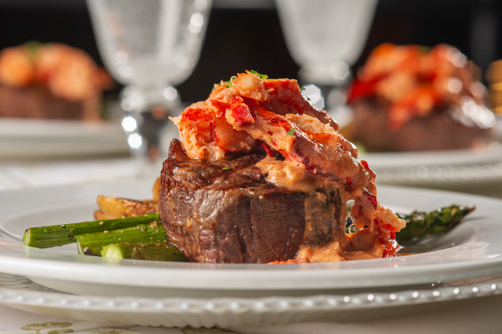 Filet mignon topped with lobster, plated with asparagus
