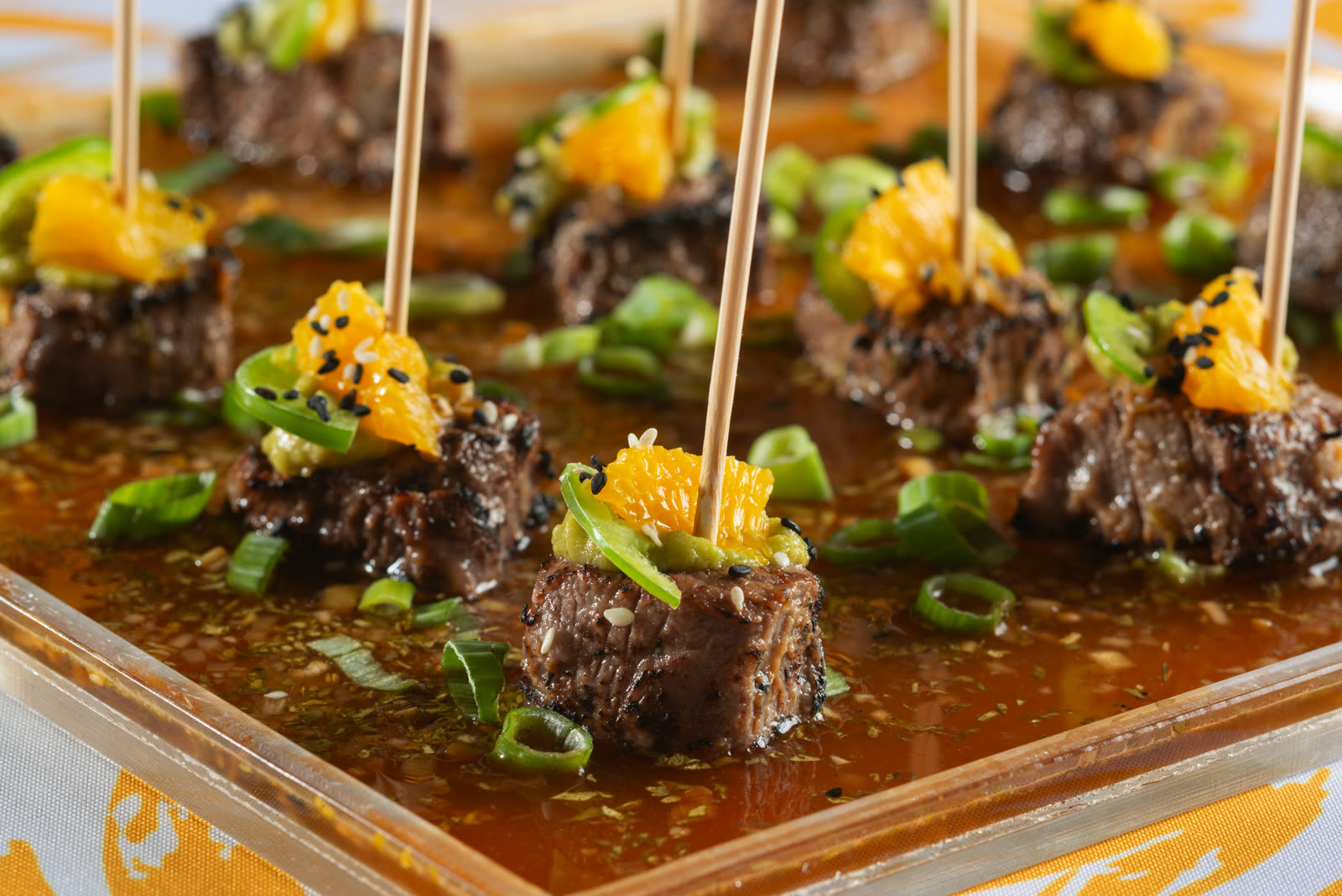 Steak-bite hors d'oeuvres on picks with citrus, avocado, and jalapeño